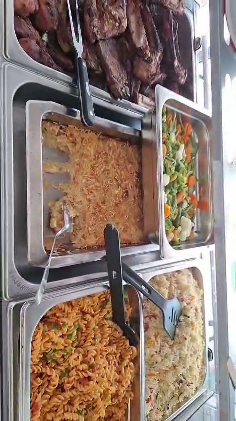 La vitrine chaude du restaurant garnie de grillades, gratin, légumes et riz